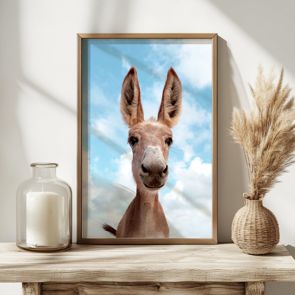 Framed picture of a donkey with a blue sky background on a wooden table.