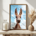 Framed picture of a donkey with a blue sky background on a wooden table.